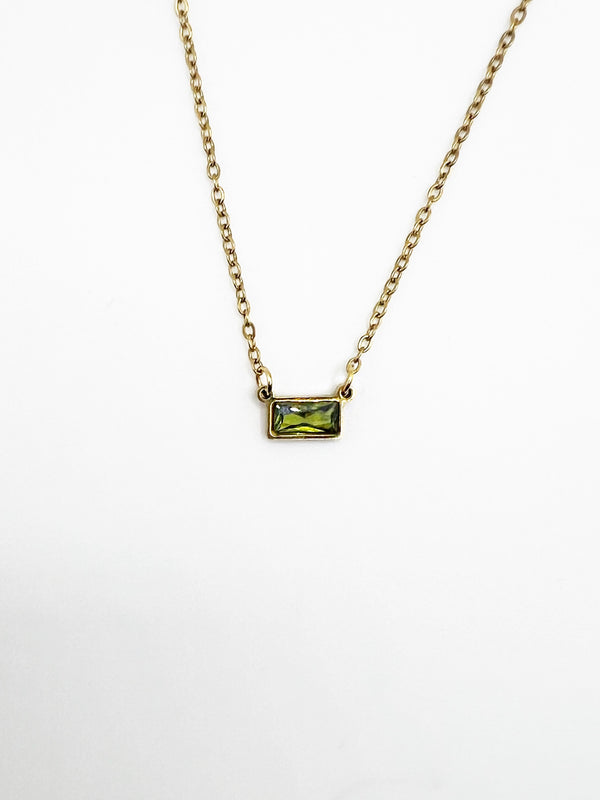 Gold necklace with a green gemstone pendant on a white background