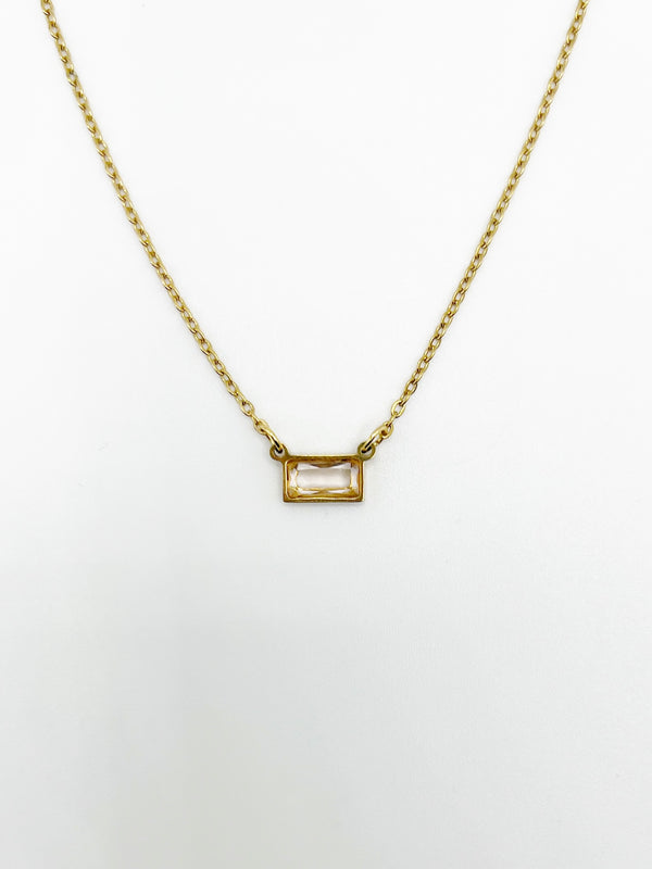 Gold necklace with a rectangular pendant on a white background