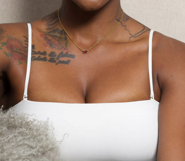 Person wearing a white top with visible tattoos and a necklace.