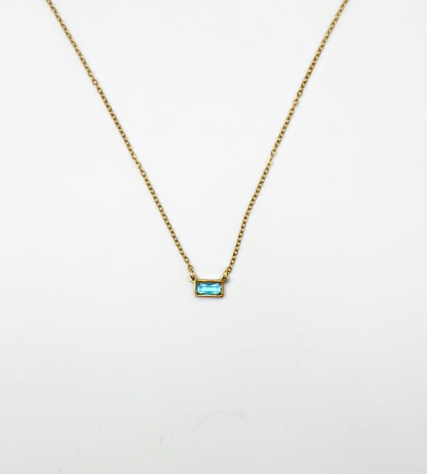 Gold necklace with a blue gemstone pendant on a white background