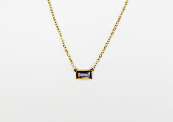 Gold necklace with a rectangular gemstone pendant on a white background