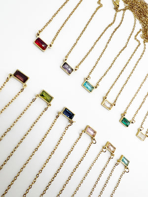 Gold necklaces with colorful gemstones on a white background